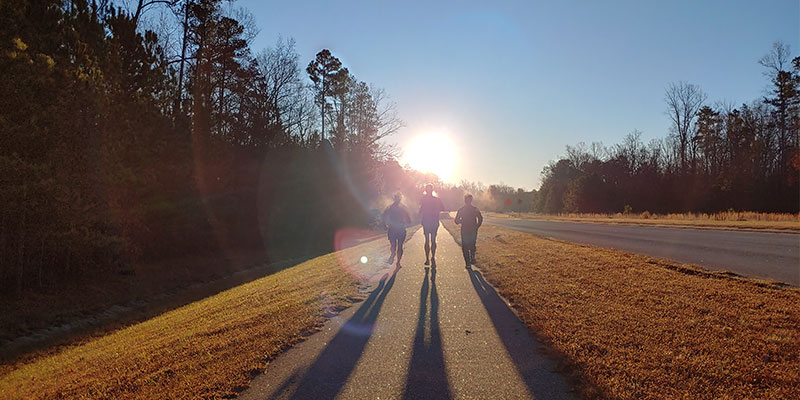 runners running towards the sun in January